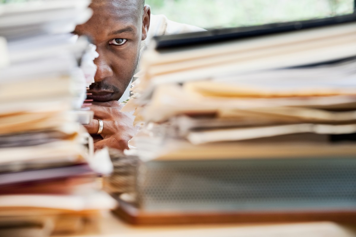 businessman hiding behind stack of paperwork