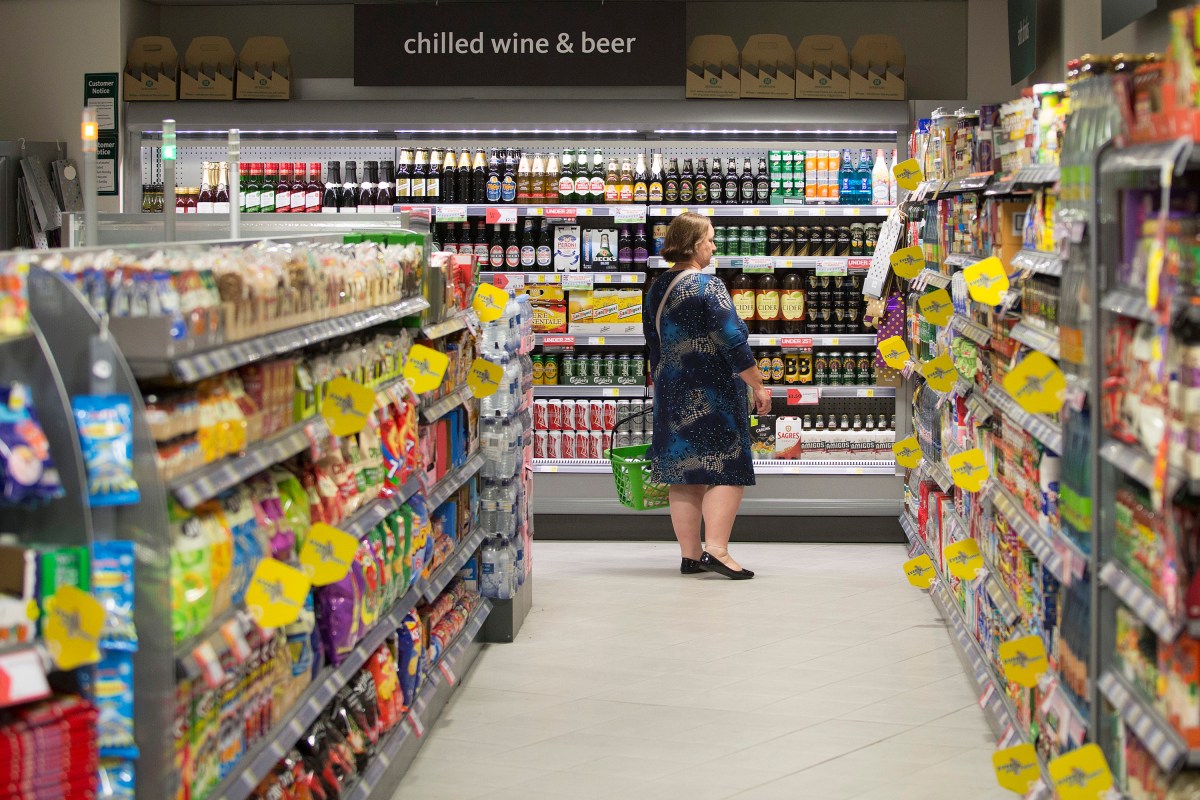 A customer holds a shopping basket as she browses the wine and beer section inside a Morrisons M Local store